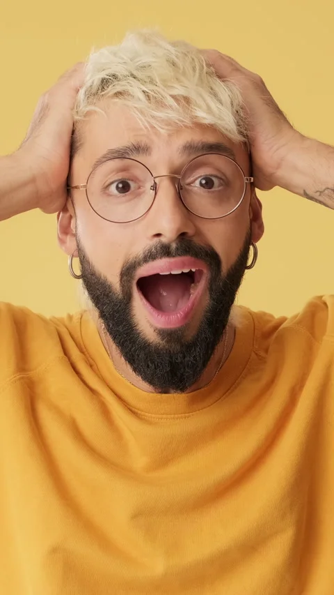 Amazed man looking at camera with big eyes, puts hands on head, isolated on Stock Footage 253935455