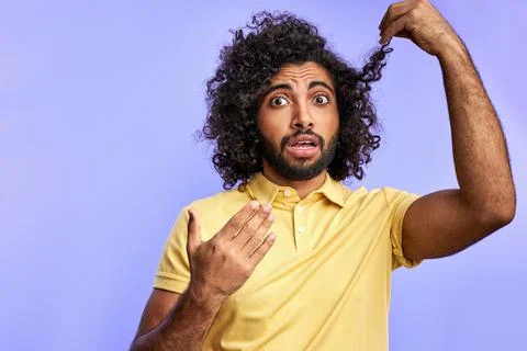 Amazed man looking at camera holding hair ends Stock Photos