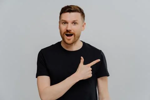 Amazed man pointing at upper right corner, found out special offer Stock Photos