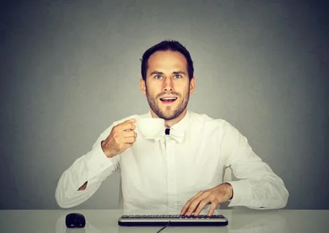 Amazed man using computer holding cup of coffee. Stock Photos