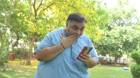 Amazed overweight indian man using smart phone. Plus size guy holding mobil.. Stock Footage 312848372