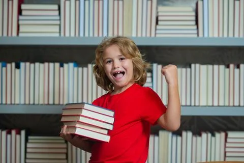 Amazed school kid hold stack of books. Successful excited school kid. Kid reads Stockfoto's