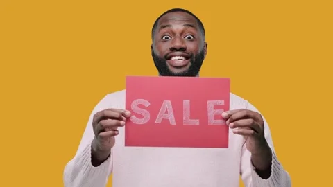 Amazed young black man guy Hold banner with SALE title, on yellow background Stock Footage 142794177