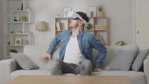 Amazed young man using his VR headset for watching the 360 video while sitting Stock Footage 169320800