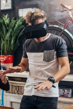 Amazed young man wearing virtual reality goggles playing an interactive game Stock Photos
