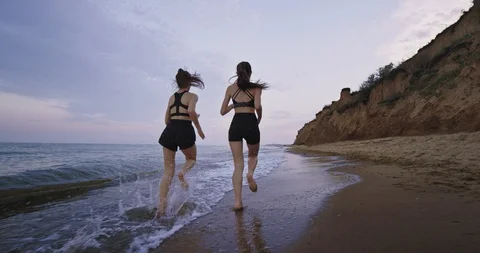 Amazing beach view two pretty ladies running together in the morning get some Stock Footage 115200517