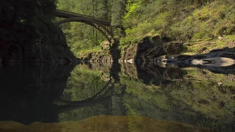 Amazing bridge in forested canyon with reflection on river Stock-Footage 107616506