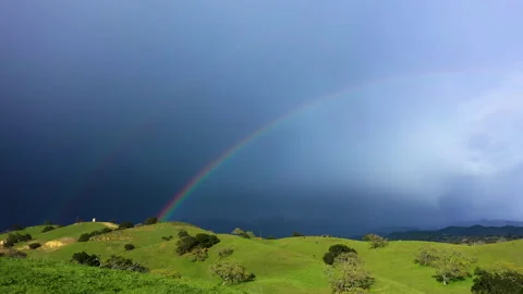 Amazing double rainbow over cattle on rolling green hill farmland with snowy Stock Footage 150235322