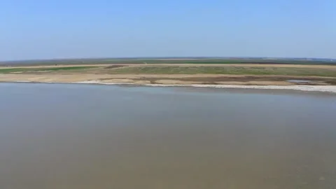 Amazing drone footage capturing large lake and land on shore under blue sky Stock-Footage 270501963