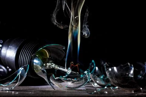 Amazing explosion of a burning light bulb with splinters and smoke on a black Stock Photos
