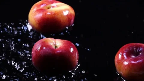Amazing flat peaches, falling on black surface with shallow water Video stock 78353919