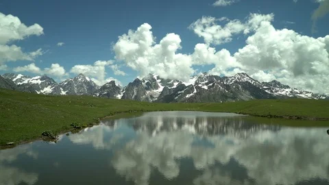 Amazing nature. Clouds reflected  in mountain lake. Snow capped mountain peaks. Video stock 115964644