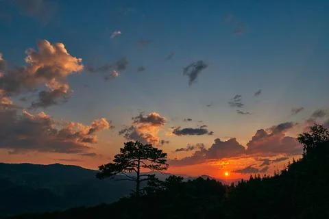 Amazing orange sunrise from behind the clouds in the mountains. Multi-colored Stock Photos