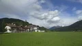 Amazing panorama of green valley with houses and Dolomites mountain range, Italy 4k or 4k+ Resolution