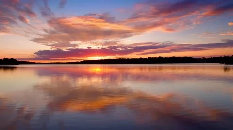 Amazing red sunrise reflected in calm waters, seamless loop Stock Footage