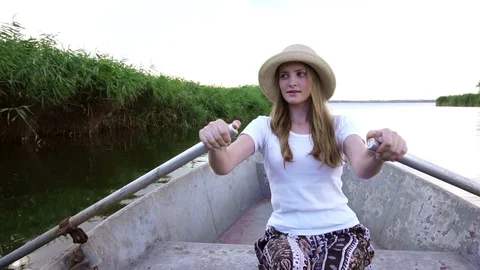 Amazing slow motion view on tender romantic girl rower in straw hat sailing on Stock Footage 95409922