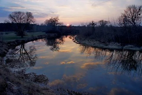 Amazing sunset over the river with a mirror reflection of clouds in the water. Stock Photos