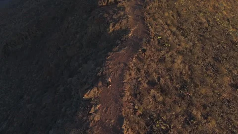 Amazing top down aerial view of a woman hiking on a dirt path along a steep Stockbeeldmateriaal 333096169