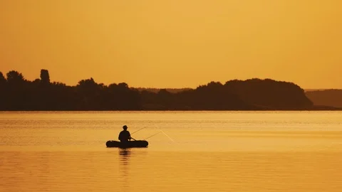 Amazing view of the evening sunset and a man in a boat fishing. Stock Footage 111433940