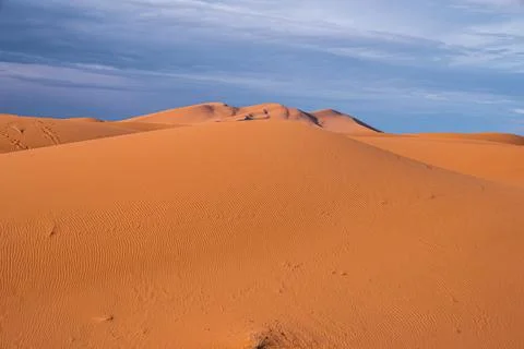 Amazing view of sand dunes with waves pattern in desert against cloudy sky Foto stock