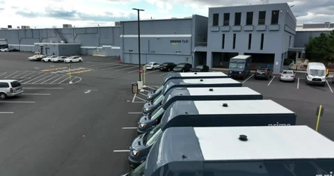 Amazon delivery vans and trucks, aerial rising to Amazon Hub warehouse Stock Footage 167878844