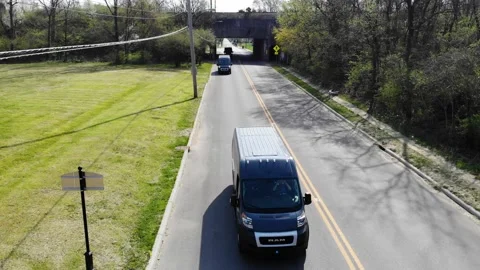 Amazon delivery vans drive down a city street recorded by an aerial drone Stock Footage 152161161