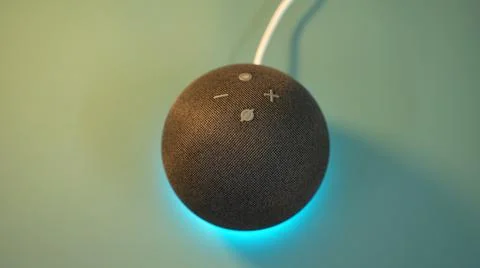 An amazon echo dot on a green wall with blue ambient lights with white cable Stock Photos