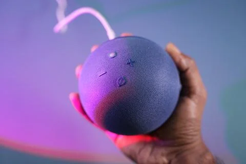 An amazon echo dot on hand with ambient lights Stock Photos