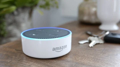 Amazon Echo Dot lights up with a blue light ring on a tabletop.  Editorial clip. Video stock 103319346