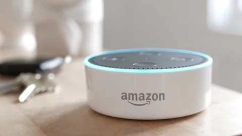 Amazon Echo Dot lights up a blue ring on a desk after a command. Editorial clip. Video stock 103321252