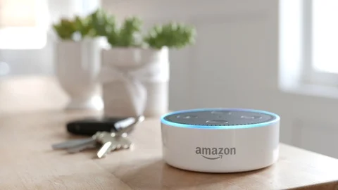 Amazon Echo Dot sits in front of keys on a wood table.   Editorial clip. Video stock 103320707