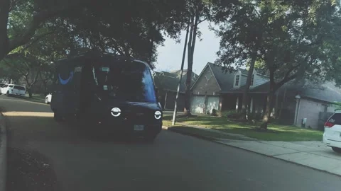 An Amazon electric delivery van delivers packages in a residential Stock Footage 256653927