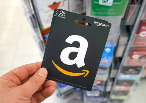 Amazon gift card in a hand at store over gift cards. Photos