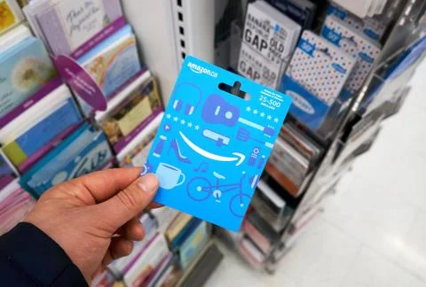 Amazon gift card which never expires in a hand over a stand with gift cards. Fotos Stock