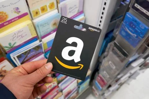 Amazon gift card which never expires in a hand over a stand with gift cards. Фото
