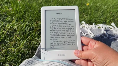 Amazon Kindle e-book reader in hand outdoor Stock-Footage 250454042