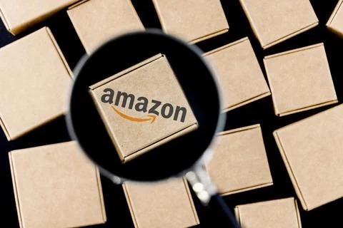 Amazon logo on box under magnifying glass surrounded by parcels Stock Illustration