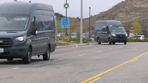 Amazon Prime Delivery Vans departing hub on to a street Stock Footage