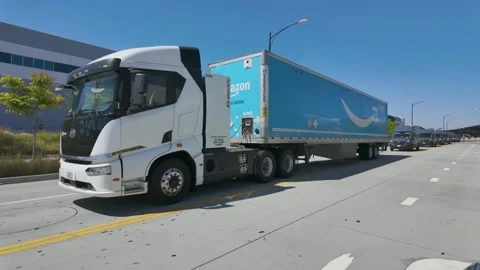 Amazon Prime delivery vans, trucks departing Amazon warehouse distribution hub Stock Footage 333537728