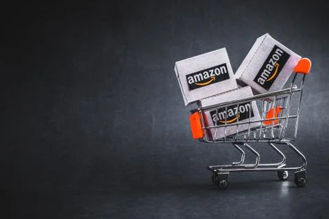 Amazon shipping packages boxes and shopping cart on black background 库存照片