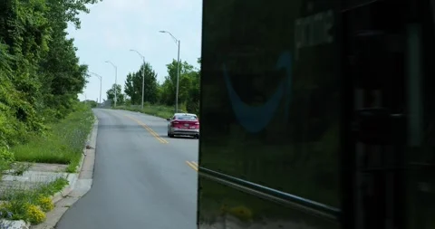 Amazon van drives close by camera while others turn onto road Stock Footage 338197082