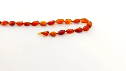 Amber Beads in Motion: Warm Tones on Clean White Backdrop Stock Footage 318948509