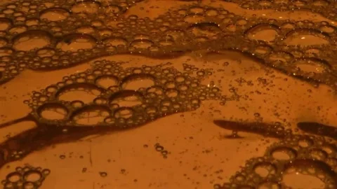 Amber bubbles moving and popping on a viscous liquid surface. Stock Footage 330570900