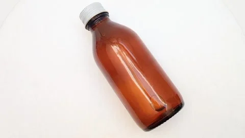 Amber glass bottle with cap rotating on white background, brown glass bottle Video stock 331978595
