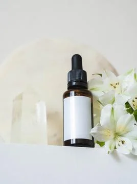 Amber glass bottle down up on table and white flowers and big cristal on whit Stock Photos
