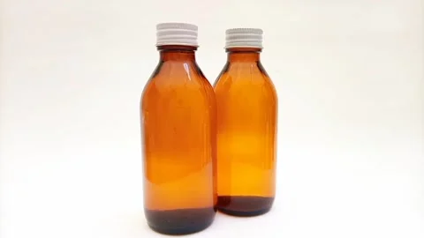 Amber glass bottles with cap rotating on white background, brown glass bottles  Видео 331978558