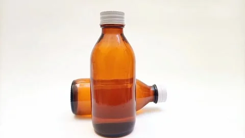 Amber glass bottles with cap rotating on white background, brown glass bottles  Видео 331978596