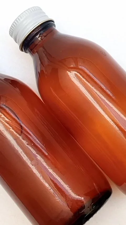 Amber glass bottles with cap rotating on white background, brown glass bottles  Video stock 331978770