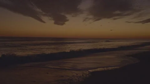 Amber Ocean Sunset with Wispy Clouds and Gentle Waves Crashing on Beach Shore Stock Footage 328131643