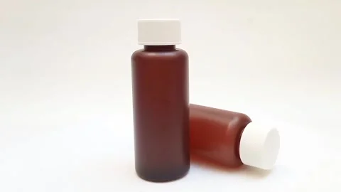 Amber plastic bottles with cap rotating on white background, brown plastic .. Video stock 331978775